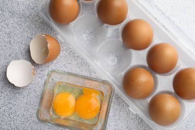 Bir sürü çiğ tavuk yumurtası ve kırık yumurta gri masada, düz yatıyordu.