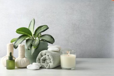 Beautiful spa composition with herbal bags and burning candle on white table, space for text