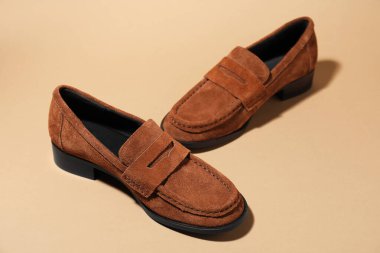Pair of stylish brown shoes on beige background, closeup