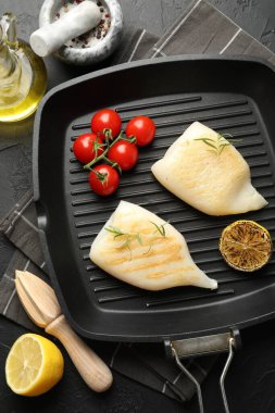 Lezzetli ızgara kalamar, domates, limon, biberiye ve biber parçaları koyu dokulu masada, düz yerde.