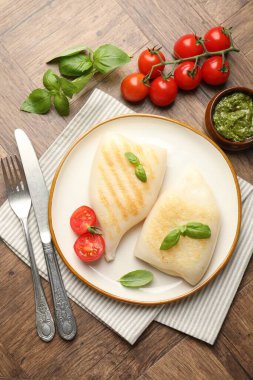 Lezzetli ızgara kalamar, domates, fesleğen ve sos parçaları ahşap masada, düz yatıyordu.