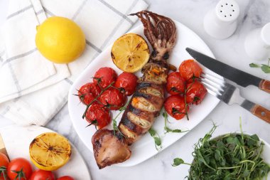 Lezzetli doldurulmuş mürekkep balığı, mikroyeşiller, limon ve domatesler beyaz mermer masada, düz yerde.