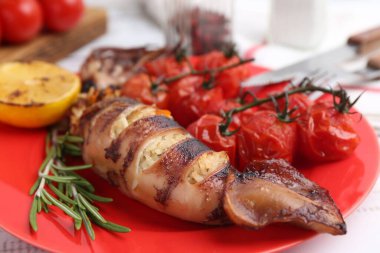 Lezzetli dolma kalamar, biberiye, limon ve domatesler ışık masasında, yakın plan.