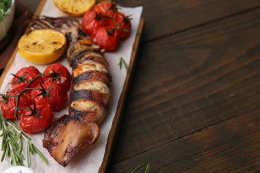 Lezzetli dolma kalamar, biberiye, limon ve domatesler ahşap masada, yakın plan. Metin için boşluk