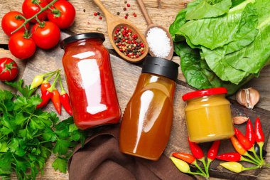 Farklı lezzetli soslar ve sebzeler ahşap masada, düz yerde.