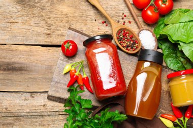 Farklı lezzetli soslar ve sebzeler ahşap masada, düz yerde.