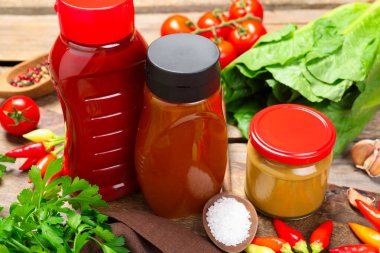 Farklı lezzetli soslar ve sebzeler ahşap masada, yakın plan.