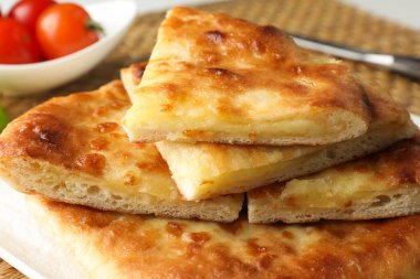 Lezzetli Megrelian Khachapuri parçaları ve masadaki ürünler, yakın plan.