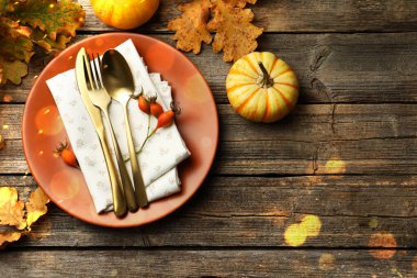 Sonbahar mekanı dekorasyonu, Bokeh ışıkları. Tabak, çatal bıçak, altın yapraklar ve balkabakları ahşap masa, üst manzara