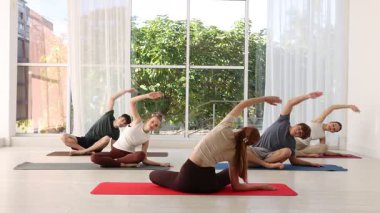 Bir grup ergen ve eğitmen içeride minderlerde yoga yapıyor.