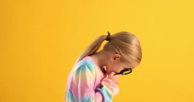 Sarı arka plandaki büyüteçten etrafa bakan tatlı kız.