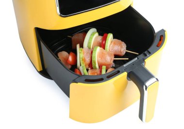 Kızartma makinesinde çiğ tavuk ve sebzeli şişler beyaza izole edilmiş.