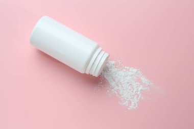 Pembe arka planda bir şişe talk pudrası.
