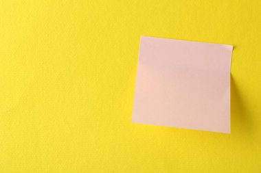 Sarı arka planda boş pembe bir not, üst manzara. Metin için boşluk