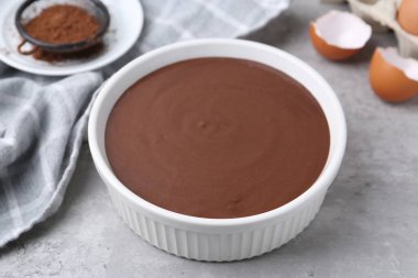 Gri masadaki kasede sıvı çikolata hamuru, yakın plan.