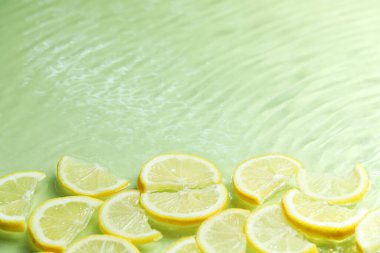 Açık yeşil arka planda limon dilimleri, yakın plan. Metin için boşluk