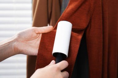 Tiftik silindirli kazak temizleyen kadın, yakın plan.