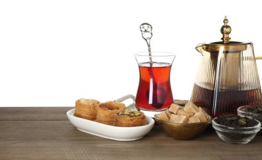 Geleneksel Türk çayı, tatlıları, kuru yaprakları ve beyaz arka plandaki ahşap masa üzerindeki şekeri