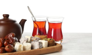 Geleneksel Türk çayı ve tatlıları beyaz arka plana karşı ahşap masada