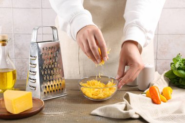 Ahşap masada rendelenmiş peynirli kadın, yakın plan.