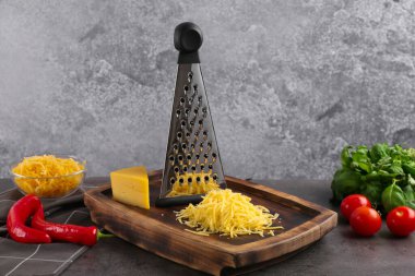 Gri masada rendelenmiş peynir, rende ve ürünler