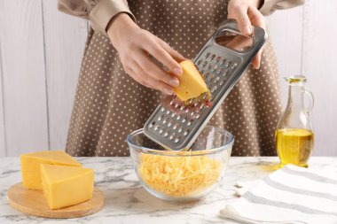 Beyaz mermer masada peynir rendeliyor, yakın plan.