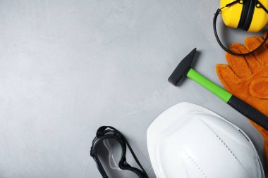 Açık gri arka planda farklı güvenlik ekipmanları ve çekiç düz yerde. Metin için boşluk