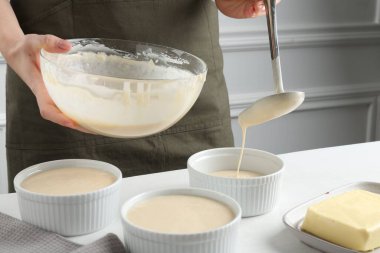 Kadın hamur hamurunu (sıvı hamur) içerideki masada yemek tabaklarına döküyor, yakın plan.