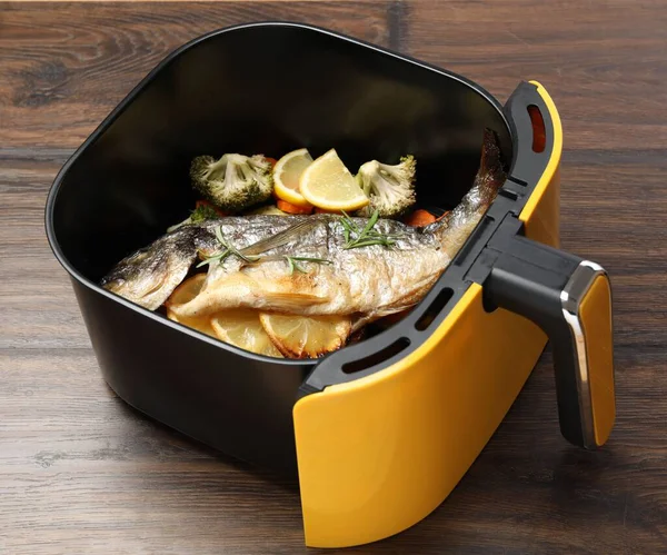 Pişmiş balık, limon ve sebzeler ahşap masanın üstünde, yakın plan.