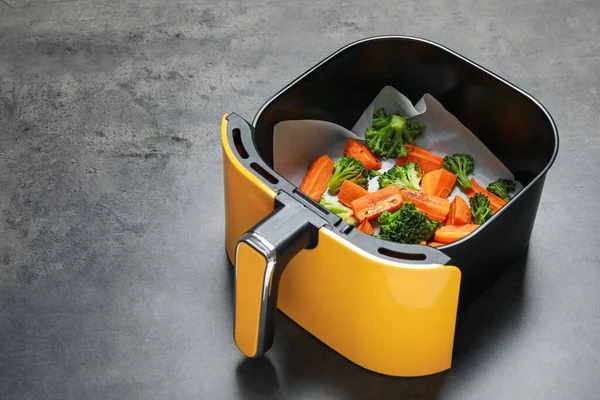 Izgara sebzeler, hava kızartma sepetinde, gri masada, yakın plan. Metin için boşluk