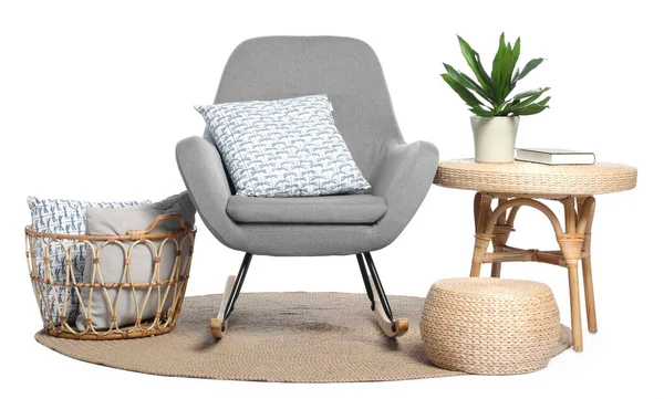 Yastıklı, halılı, sehpalı ve yeşil çiçekli sallanan sandalye beyaza izole edilmiş.