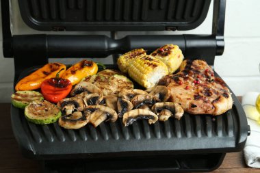 Mutfaktaki ahşap masada biftek ve sebzeli ızgara, yakın plan.