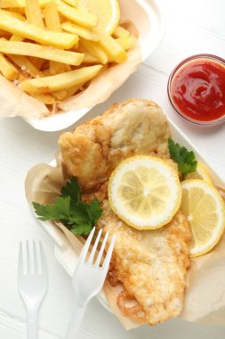 İngiliz Geleneksel Balık ve patates kızartması, beyaz ahşap masa üzerinde sos ile servis edilir.