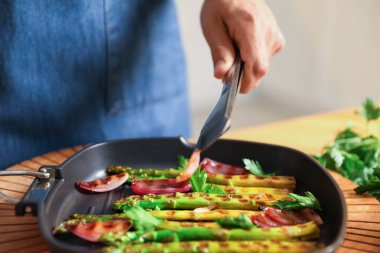 İçerideki masada soğan ve ızgara sebze ekleyen adam, yakın plan.