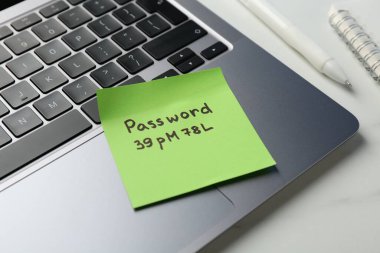 Beyaz mermer masaya parola, dizüstü bilgisayar ve kırtasiye malzemesi, yakın plan.