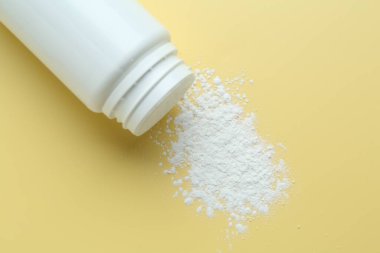 Sarı arka planda bir şişe talk pudrası.
