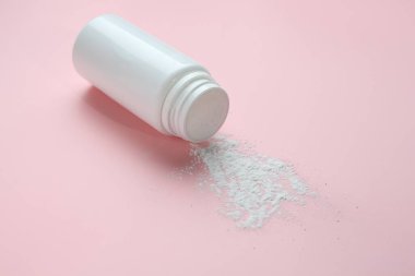 Pembe arka planda bir şişe talk pudrası.