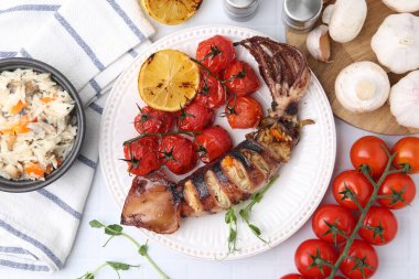 Lezzetli doldurulmuş mürekkep balığı, mikro yeşillikler, limon, domates ve diğer ürünler beyaz fayanslı masa, düz yatak