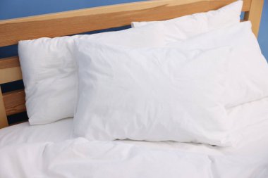 Mavi duvarın yanında sıcak, temiz çarşafları olan bir yatak, yakın plan.