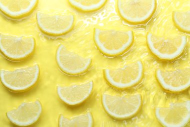 Sarı zemin üzerinde limon dilimleri, düz uzanmış.