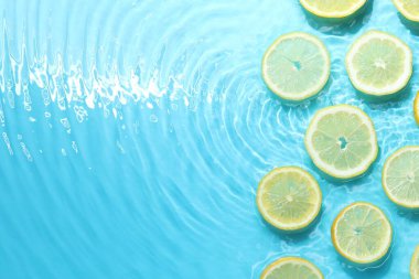 Açık mavi arka planda limon dilimleri, düz. Metin için boşluk