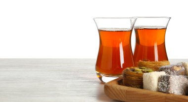 Geleneksel Türk çayı ve tatlıları beyaz arka plana karşı ahşap masada