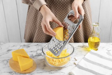 Beyaz mermer masada peynir rendeliyor, yakın plan.