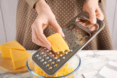 Beyaz mermer masada peynir rendeliyor, yakın plan.