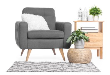 Yastıklı, komodinli, halı ve dekorlu rahat bir koltuk.