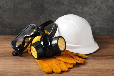 Sert şapka, koruyucu eldivenler, gözlükler ve ahşap masada solunum cihazı. Güvenlik ekipmanları