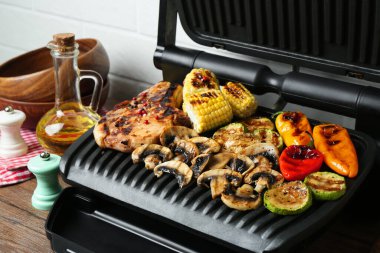 Mutfaktaki ahşap masada biftek ve sebzeli ızgara, yakın plan.