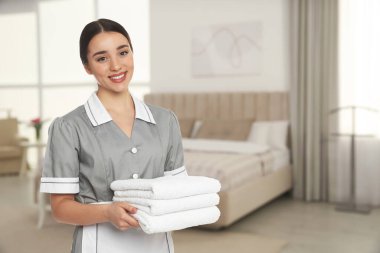 Otel odasında temiz havluları olan oda hizmetçisi