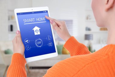 Odadaki tablet bilgisayarda akıllı ev uygulaması kullanan kadın, kapat