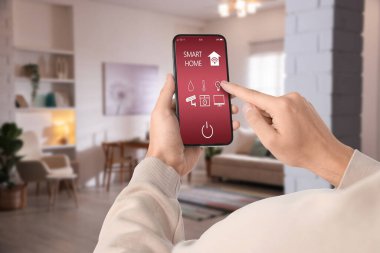 Adam cep telefonunda akıllı ev uygulaması kullanıyor.